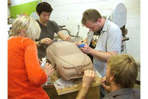 Students working together on a clay car model.